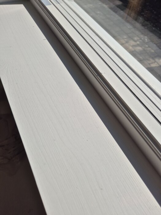 Målad fönsterbräda i obehandlat furu med synlig träådring.