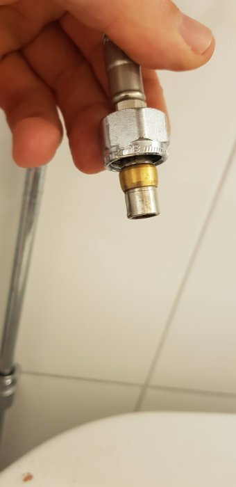 Hand håller metallkoppling med slätända och packning.