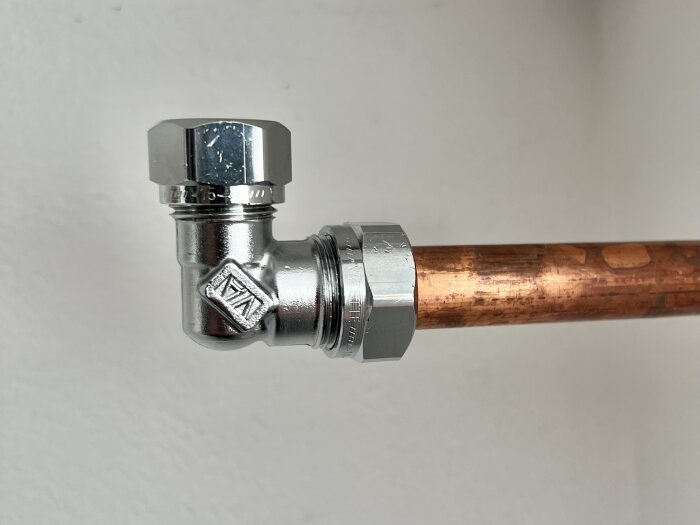 Kopparrör anslutet till en metallisk 90 graders klämringskoppling.
