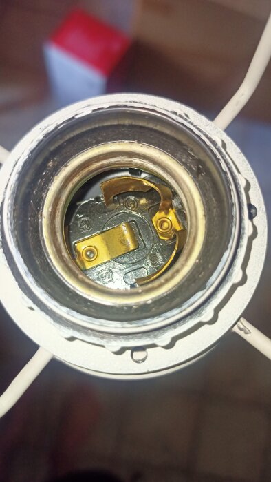 Närbild av insidan av en glödlampas sockel, med metallkontakter synliga.