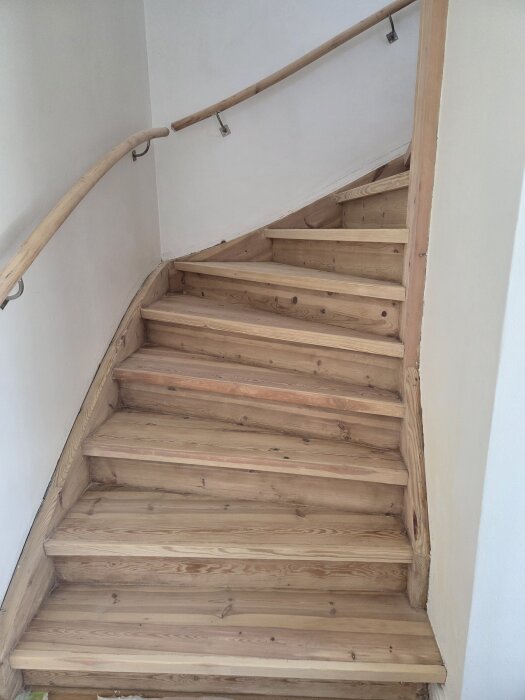 Trappa i trä med fläckig yta, behandlad med vitpigmenterad såpa. Trappstegen har varierande färgtoner och ser något tryckimpregnerade ut.