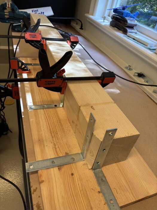 Träbit fastklämd med vinkeljärn på en träskiva, redo för slipning.