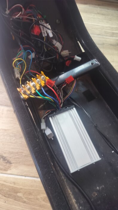 Kablage och elektronisk kontrollbox i ett fack med flera färgade och vita kablar, anslutna till en terminal.