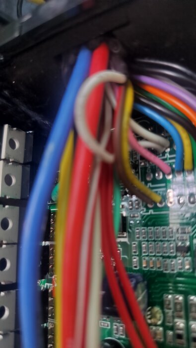Flera färgade kablar, inklusive vita, anslutna till kretskort i en elektronisk enhet.