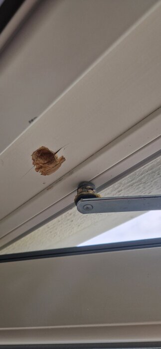 Skadad dörrkarm med lossad dörrbroms och synligt hål där gängorna saknas.