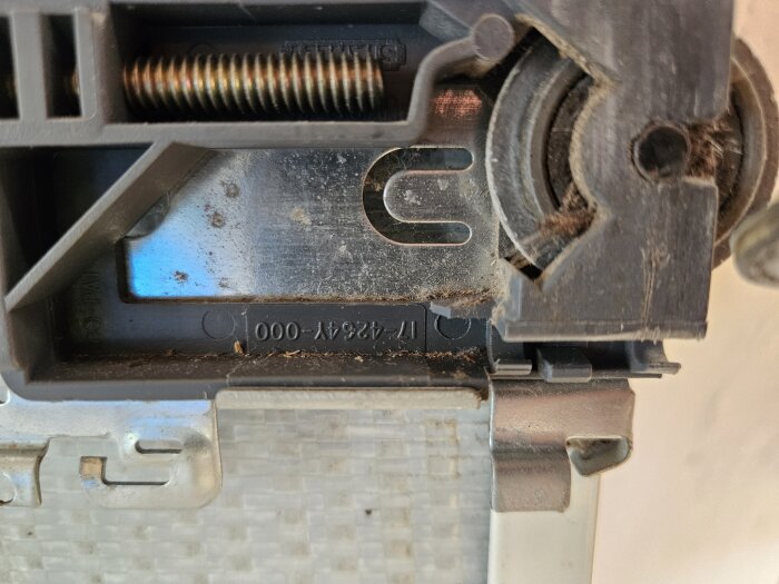 Närbild av hjulmekanism för spegelskjutdörr, märkning "17-4264y-000," delvis i plast och metall med synliga skruvar och damm.