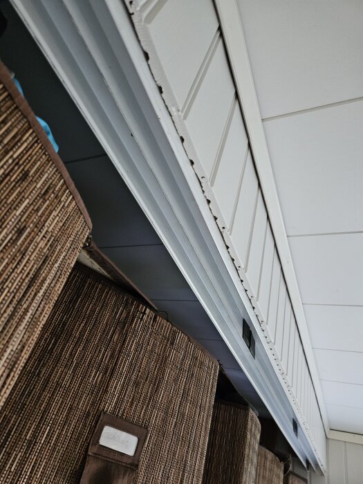 Spegelskjutdörrar med takskena synlig, ovanför bruna korgar i en hall.