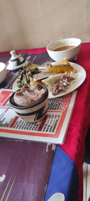 Lunchtallrik i Kampala med köttgryta, irländsk potatis, matoke, pumpa, spenat, samt en skål med ugali.