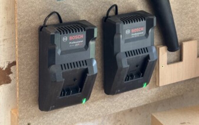 Två Bosch-laddare monterade på en vägg, med kabeln fäst upptill.