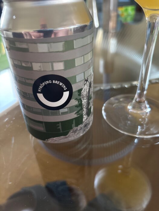 Burk med öl från "Nyköping Brewing" och ett glas på ett bord.