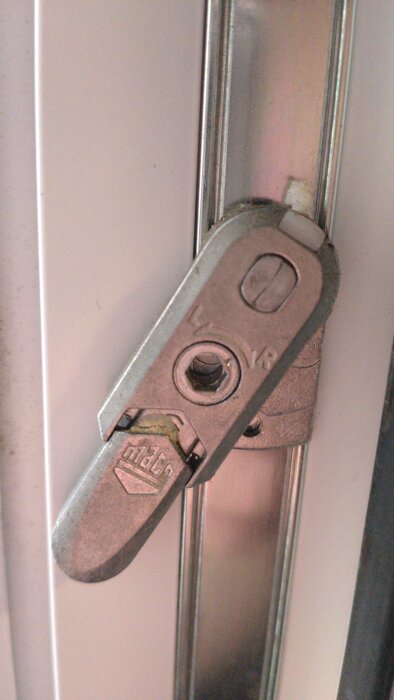 Fönsterbeslagets spärr på en spanjolett, detalj av mekanism, metallfärg.