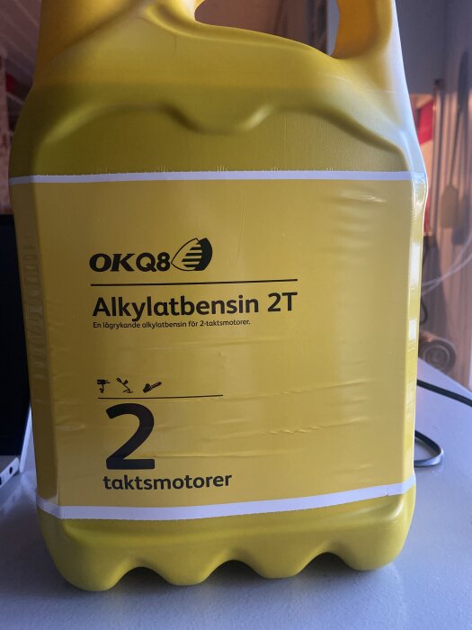 Gul dunk av OKQ8 alkylatbensin 2T för 2-taktsmotorer, utan märkbar information om tillsatt olja.
