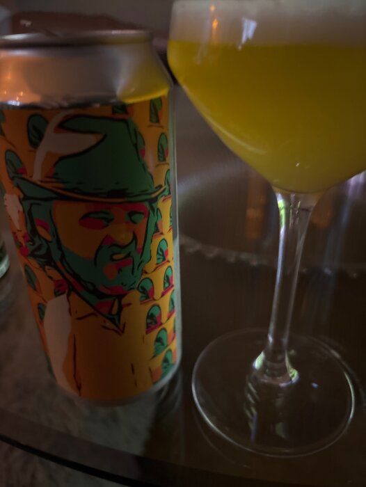 Ölburk från Nyköping Brewery med motiv av en man i hatt, bredvid ett glas fyllt med Neipa.