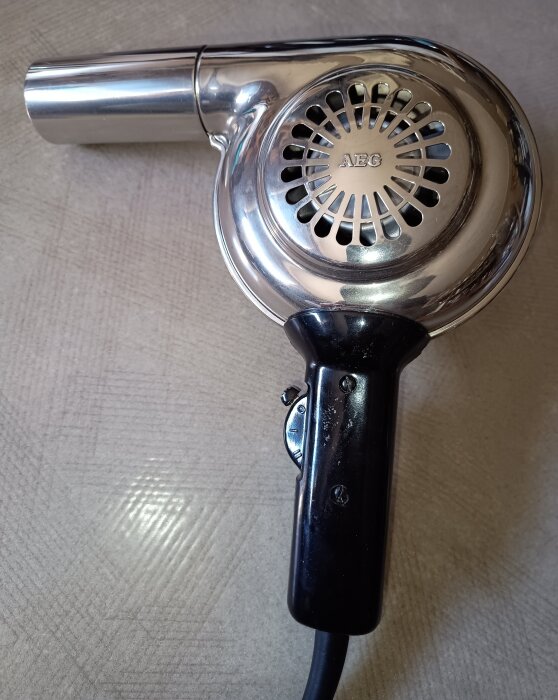 Klassisk AEG hårtork i metall med bakelithandtag och industriell design.