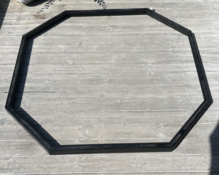 Octagonformad träram för strategispel, byggd av målad trälist, placerad på ett trädäck.