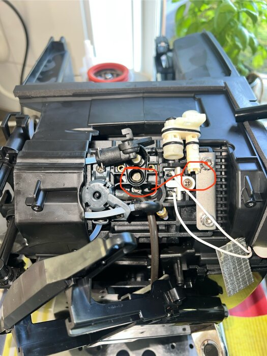 Inuti en delvis isärtagen DeLonghi Magnifica S kaffemaskin, med ett inringat område som visar läckage nära ett vitt munstycke.