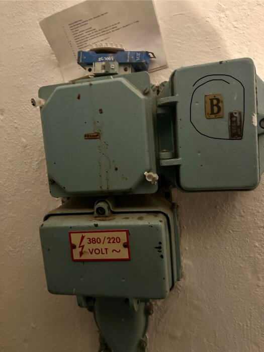 Gammalt elskåp med märkning för huvudsäkring "B" med varningsskylt för 380/220 volt.