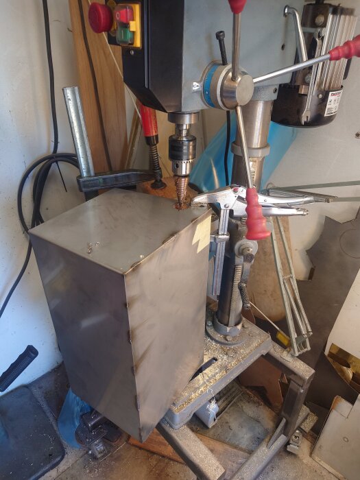 En ståltank under byggnation i en verkstad, med en borrmaskin och verktyg synliga runtom.