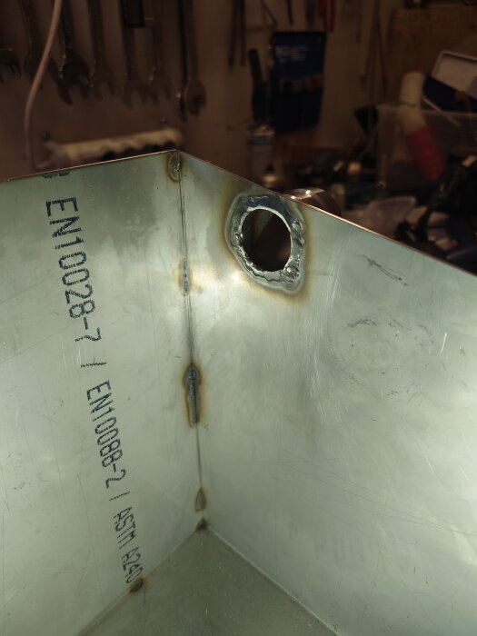 Svetspunktade hörn på metalltank med röranslutning, liten skevhet i konstruktionen.