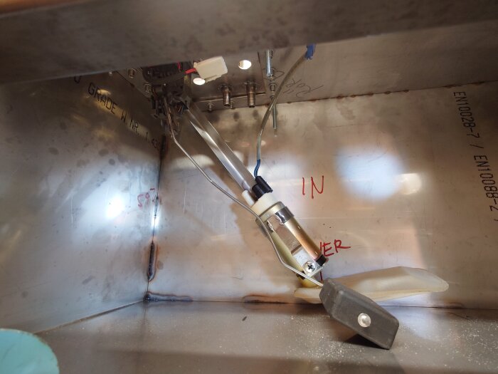 Svetsad tank med monterad armatur och synliga märken och text markerade på insida, en del är sned.