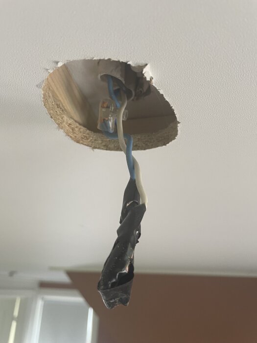 Elektrisk installation i tak med blå och vit kabel, kopplas med kontakt och isoleringstejp runt anslutningen.