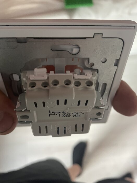Närbild på en vit elektrisk koppling med flera anslutningar och märkning 16A 250V på baksidan av en väggplatta.