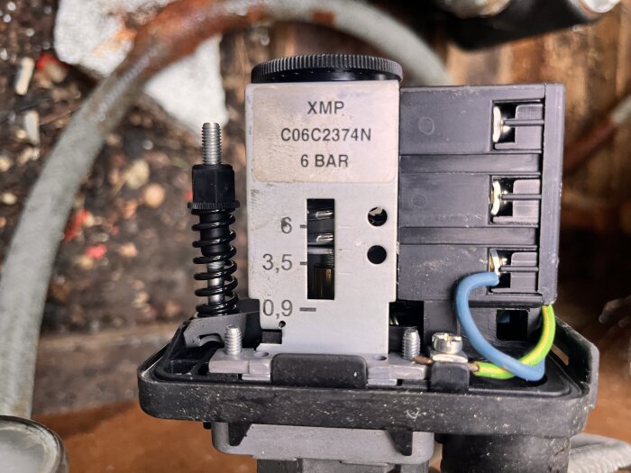 Tryckströmbrytare med märkning XMP C06C2374N 6 BAR, justerskruv och anslutna kablar synliga.
