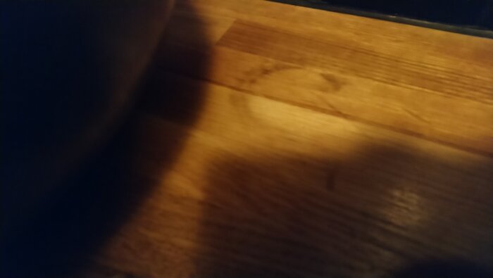 Trägolv med ljus fläck, partiellt slipad, synbar skugga.