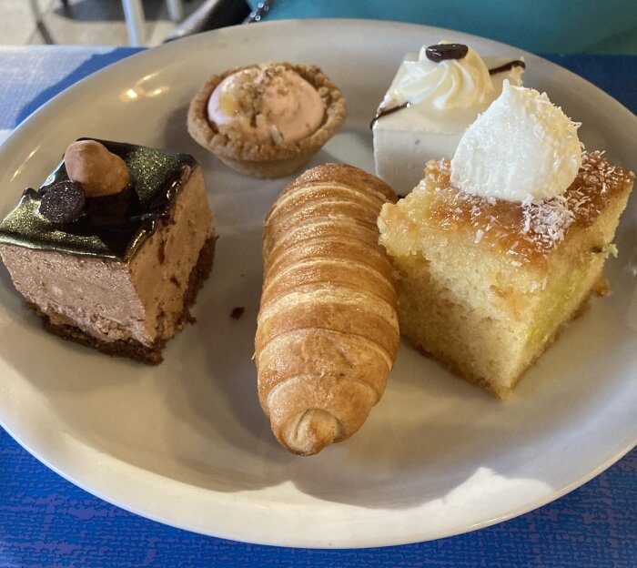 En tallrik med olika desserter, inklusive bakverk och kakor, på ett bord.