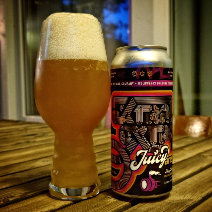 Glas och burk med Weldwerks Juicy Bits öl på träbord.