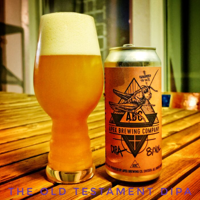 En glas öl med skumhuvud bredvid en burk med etiketten "Apex Brewing Company DIPA" på ett bord.