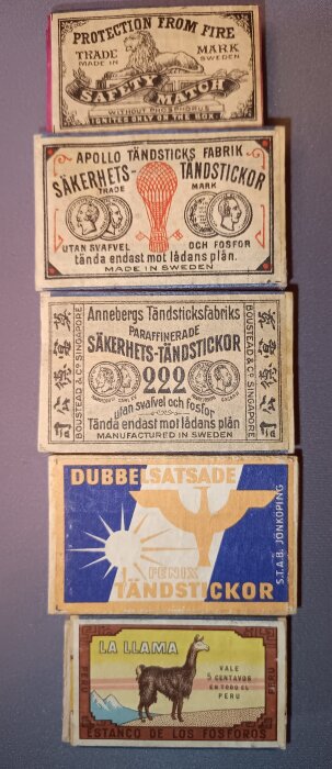 Fem gamla tändsticksaskar med olika etiketter, inklusive motiv av en lejon, luftballong, fågel och en lama. Askarna är från Sverige och Peru.