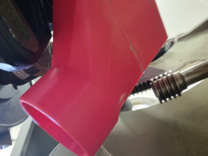 3D-printad röd del avlångt format, designad för att minska tvärsnittsarea för 100mm slang, monterad på maskin.