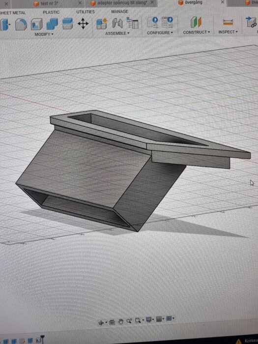 3D-modell av en rektangulär adapter designad i Fusion 360, liggande snett på ett rutnät. Modellen visas i grå färg, skapad för 3D-utskrift.