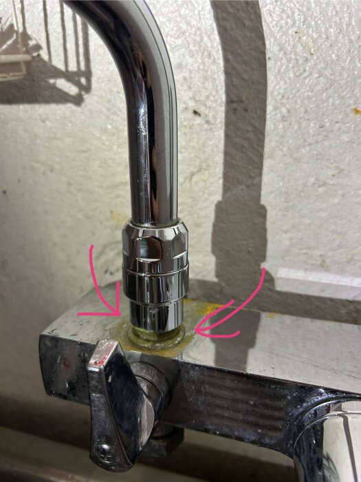 Kran med läckande blandarfäste, pilar markerar platsen.