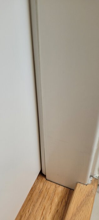 Skewed bathroom door showing gap at the bottom, implying misalignment with the frame.