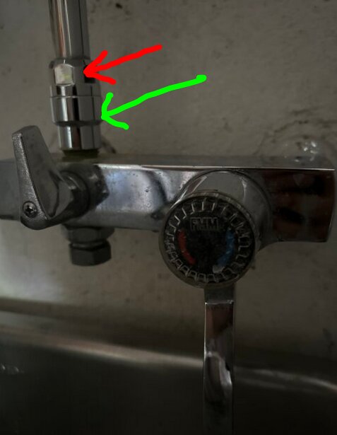 Vattenkran med en röd pil som pekar på en mutter och en grön pil som pekar på "förstoringen" under kranen.
