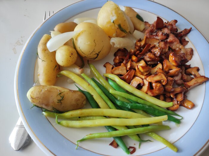 Tallrik med färskpotatis, kantareller, charlottenlök, bönor och bacon, dukad för sommarlunch.