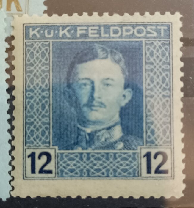 Frimärke med porträtt av man i uniform, text "K.u.K. FELDPOST" och siffran 12 i hörnen.