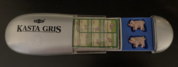 Spelsetet "Kasta Gris" med grisklossar, poängkort och förvaringslåda.