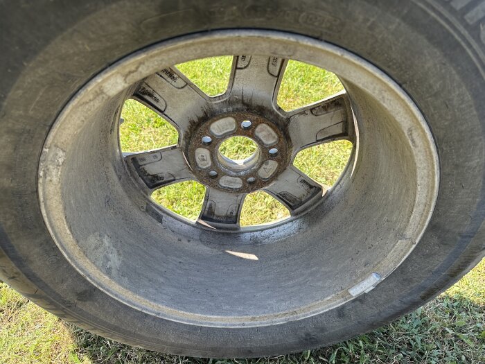 En smutsig fälg till Volvo fotad utomhus, på gräs, innan rengöringsprocessen.