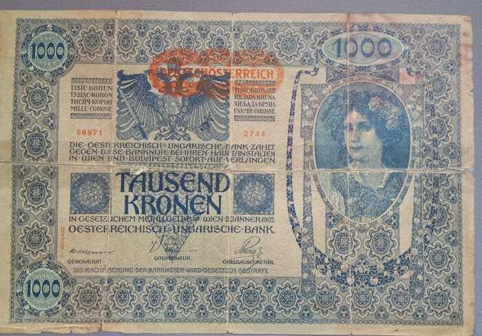 En gammal österrikisk-ungersk sedel på 1000 kronor med dekorativt mönster och porträtt av en kvinna.