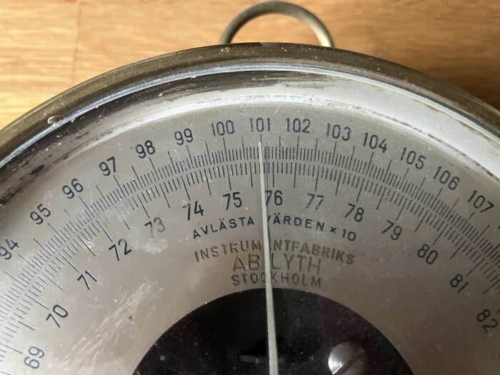 Närbild av vintage barometer från AB Lyth Stockholm med skala och markering som visar tryckmätningar, del av en diskussion om dess funktion.