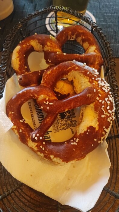 Brun kringla med salt, serverad på en servett framför ett glas öl på världens äldsta bryggeri.