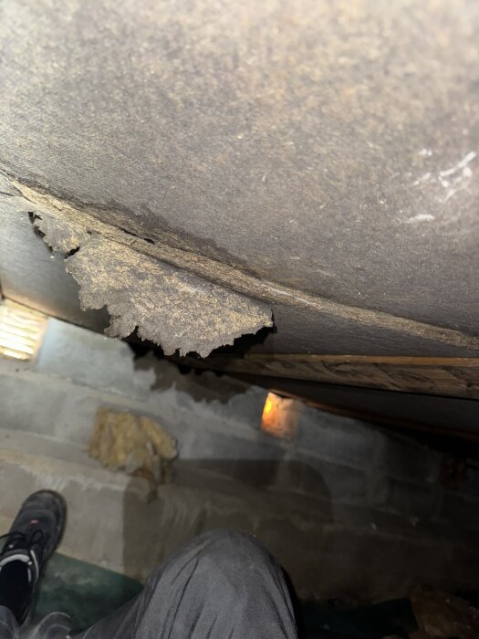 Sprucken isoleringsboard med misstänkt mögel i en krypgrund med synliga ventiler och trasig isolering på golvet.