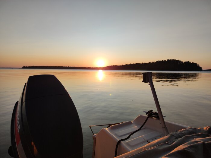 Solnedgång över sjö med båt i förgrunden.