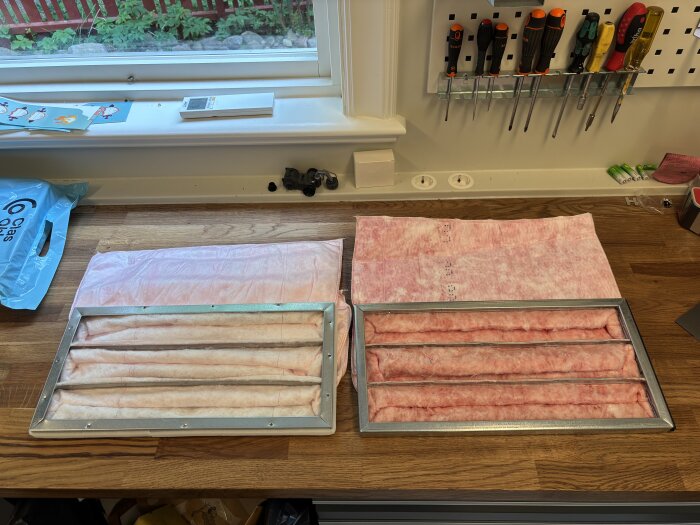 Två olika filtermaterial ligger på ett bord, det ljusare från Cleanfilter och det mörkare från Östberg, med olika texturer och tjocklekar.
