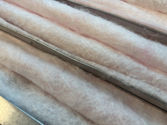 Närbild av ljusrosa filtermaterial från Cleanfilter, med en lätt syntetisk och tunnare struktur, monterat i en metallram.