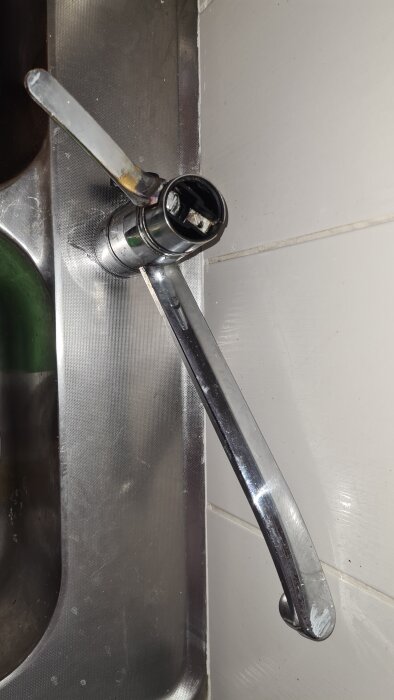 Kromad ettgreppsblandare monterad på diskbänk, sedd uppifrån. Handtaget och pipen visas mot en vit kaklad vägg.