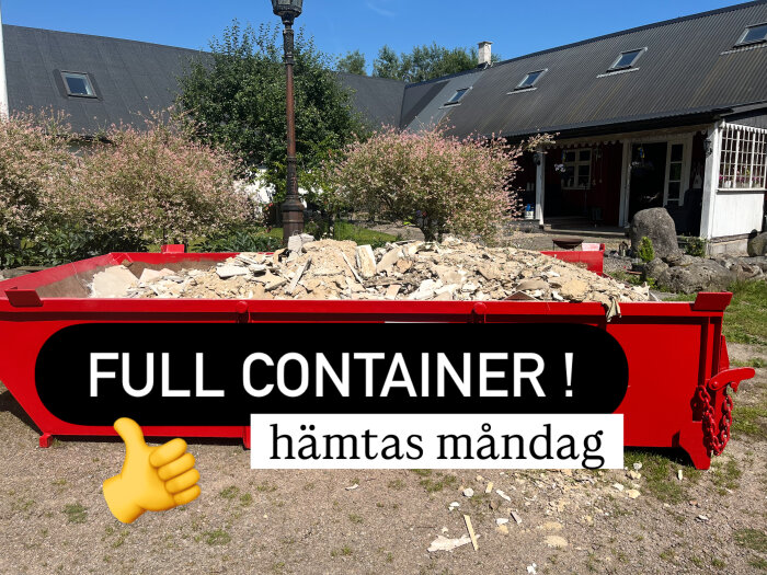 Röd container fylld med byggavfall utanför ett hus, text "FULL CONTAINER! hämtas måndag" och en tumme upp-emoji.